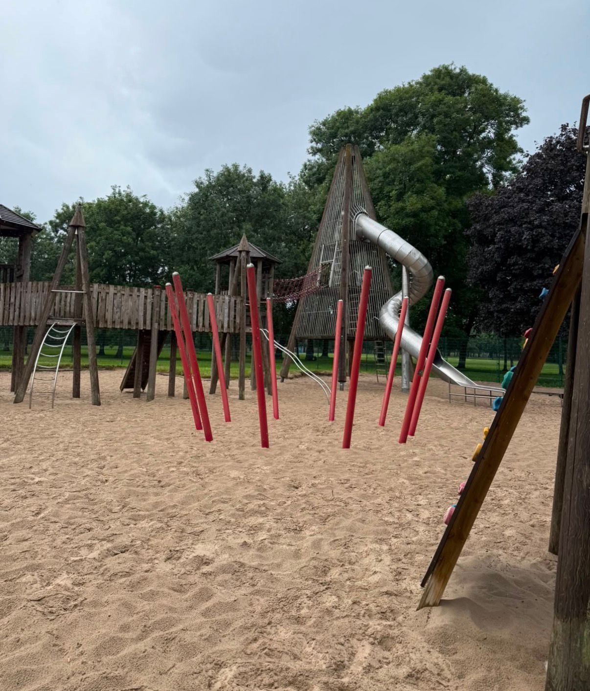 Wooden play park with climbing poles and a slide
