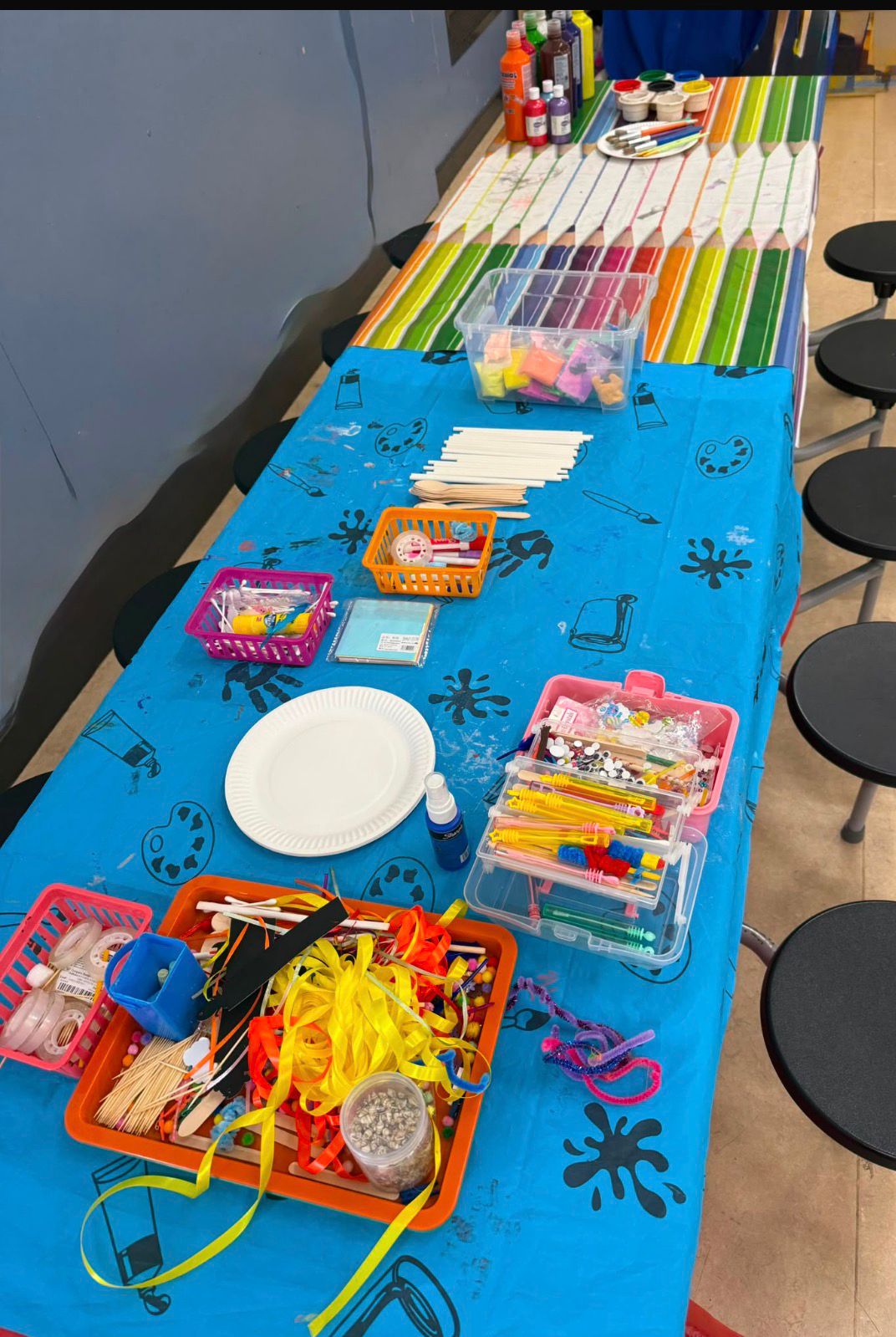 Craft table set out with paints, ribbons and pipe cleaners